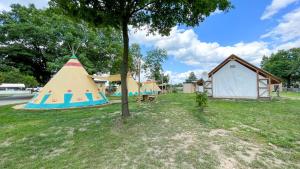 a tent and a teepee in a yard with a tree at Tipi Ottawa in Falkenberg