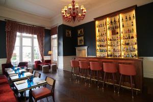 un restaurant avec un bar et des chaises rouges dans l'établissement Down Hall Hotel, à Bishop's Stortford