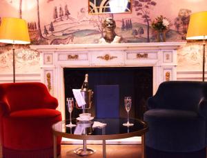 uma sala de estar com 2 cadeiras, uma mesa e uma lareira em Down Hall Hotel em Bishops Stortford