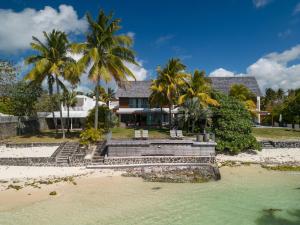 une maison sur la plage avec des palmiers dans l'établissement Villa Rubis by muse villas, à Belle Mare