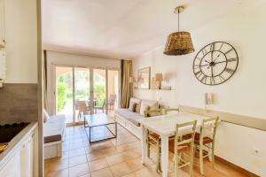 salon ze stołem i zegarem na ścianie w obiekcie Village Pont Royal en Provence - maeva Home - Studio 4 personnes - Sélection MAE-2934 w mieście Mallemort