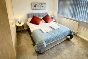 a bedroom with a bed with two red pillows at Hazel 1-Bed Flat (3) + Parking in Kidlington