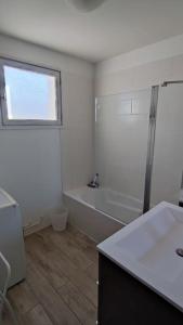 La salle de bains blanche est pourvue d'une baignoire et d'un lavabo. dans l'établissement Agréable T2 Bis Au calme proche centre-ville et plages, à Sanary-sur-Mer