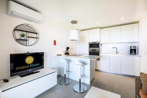 een keuken met witte kasten en een flatscreen-tv bij Résidence le Village de Cap Esterel - maeva Home - Appartement moderne 2 pi 494 in Saint-Raphaël