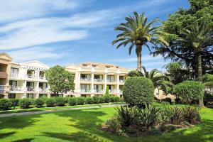 un grand bâtiment avec des palmiers et une pelouse dans l'établissement Résidence Cannes Villa Francia - maeva Home - Appartement 2 pièces 5 perso 634, à Cannes