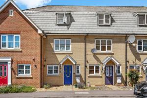 ein Backsteinhaus mit blauen Türen und Fenstern in der Unterkunft 4 Bedroom Cambridgeshire Home in Cambourne