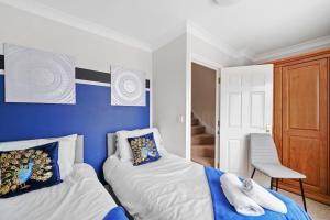 a bedroom with two beds and a blue wall at 4 Bedroom Cambridgeshire Home in Cambourne