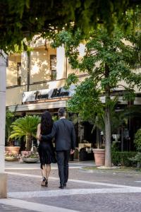 un hombre y una mujer caminando por una calle en Hotel Terme Milano, en Abano Terme