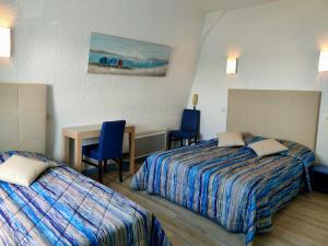 Cette chambre d'hôtel comprend deux lits, une table et des chaises. dans l'établissement Hôtel le Littoral, à Lézardrieux
