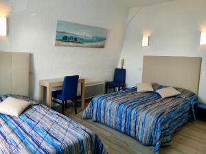 a hotel room with two beds and a table and chairs at Hôtel le Littoral in Lézardrieux