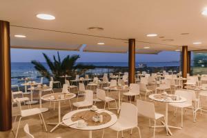 a restaurant with white tables and chairs and the ocean at Don Gregory by Dunas - Adults Only in San Agustin