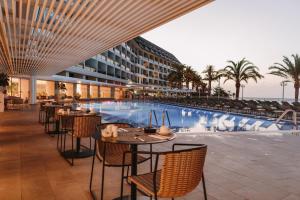 a hotel with tables and chairs next to a swimming pool at Don Gregory by Dunas - Adults Only in San Agustin
