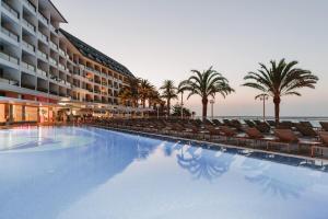 a large swimming pool with chairs and palm trees at Don Gregory by Dunas - Adults Only in San Agustin