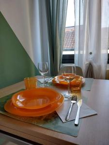 een tafel met een oranje bord en wijnglazen erop bij S.T.A.R-H.O.U.S.E Cesano Maderno (vicino Stazione) in Cesano Maderno