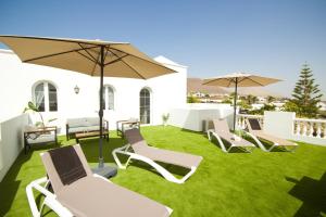 a group of chairs and umbrellas on a lawn at Casa Alba - By AZ Rentals in Tías