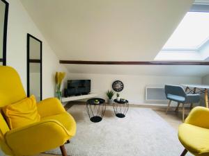 a living room with two yellow chairs and a tv at Casa Balzac – T2 in Angers