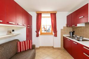 a kitchen with red cabinets and a sink at Cesa Raggio di Sole Monolocale in Livinallongo del Col di Lana