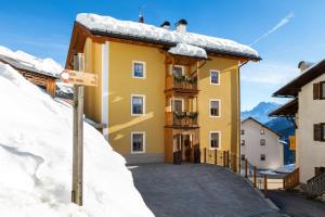 um edifício amarelo com neve na lateral em Cesa Raggio di Sole Monolocale em Livinallongo del Col di Lana