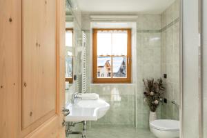uma casa de banho com um lavatório, um WC e uma janela. em Cesa Raggio di Sole Monolocale em Livinallongo del Col di Lana