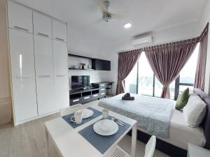 a white bedroom with a bed and a table and a tv at Inspired Homes @ PJ The Grand Sofo in Petaling Jaya