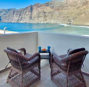 two chairs on a balcony with a view of the ocean at National Trust Beach Apartment in Santiago del Teide