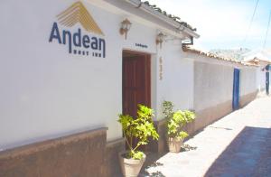 a white building with potted plants in front of it at Hotel Andean Host Inn in Cusco