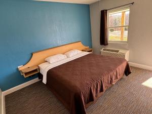 - une chambre avec un grand lit et un mur bleu dans l'établissement Budget Inn, à Thomasville