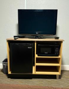 einen TV in einem Entertainment-Center mit einer Mikrowelle und einem TV in der Unterkunft Budget Inn in Thomasville