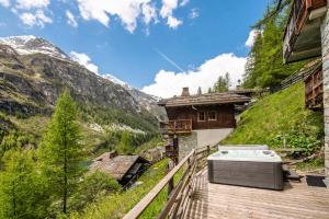 a hot tub on a wooden deck next to a building at Chalet Napoleon - Chalets pour 10 Personnes 014 in Tignes