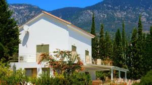 ein weißes Haus mit Bäumen und Bergen im Hintergrund in der Unterkunft Villa Telina Ideales Resort in Kefalonia