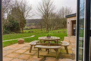 a patio with a table and benches and a view of a field at Pure relaxation at it's finest, offering moments of harmony and tranquillity - Sauna & Hot tub in Shanklin