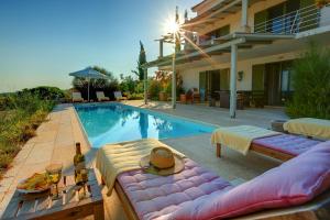 a villa with a swimming pool with a table with wine bottles at Villa Asterias Ideales Resort in Kefallonia