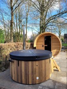 een groot houten bad op een stoep naast een gebouw bij Japandi Wellness met hottub & sauna in Ewijk