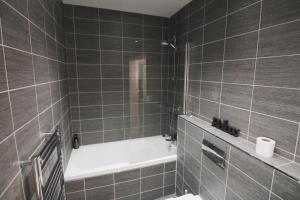a bathroom with a bath tub and a toilet at The Windsor Club Apartment in Leamington Spa