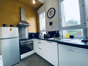 a kitchen with a white refrigerator and a sink at Casa Balzac – T3 in Angers