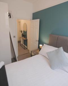 a bedroom with a white bed and a hallway at The Windsor Club Apartment in Leamington Spa