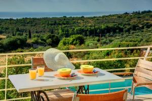 une table blanche avec deux tasses de jus d'orange dessus dans l'établissement Villa Kteni Ideales Resort, à Céphalonie