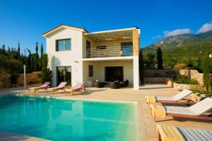 a villa with a swimming pool in front of a house at Villa Corali Ideales Resort in Kefallonia
