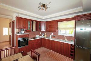 a kitchen with wooden cabinets and a refrigerator at Villa Romanza Beta in Agios Stefanos