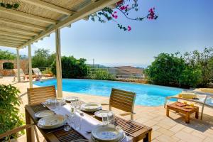 a table with plates of food on it next to a swimming pool at Villa Petalida Ideales Resort in Kefallonia +5 photos