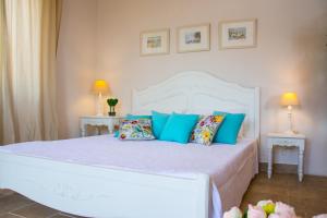 a bedroom with a white bed with blue pillows at Villa Kochilaki Ideales Resort in Kefallonia