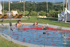 Ein Mann und eine Frau schwimmen in einem Pool voller roter Blumen. in der Unterkunft Essenziale in Castell’Anselmo