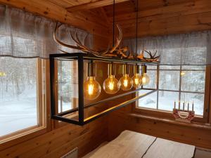 a chandelier with antlers in a room with a window at Log cabin in 15 min from Rovaniemi center- 3bdr-Sauna-Fireplace in Rovaniemi