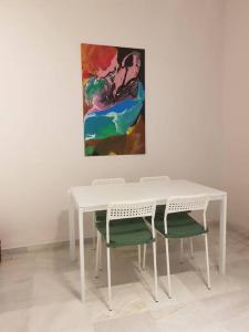 塞維利亞的住宿－Enjoy Netflix Parking según disponibilidad，一张带两把椅子的白色桌子和墙上的一幅画