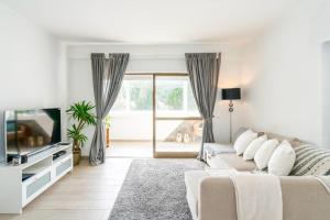 sala de estar blanca con sofá y TV en Spacious 1 bed in Vilamoura, Fast Wifi & Pool, en Quarteira