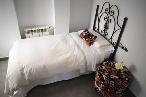 a bed with a white comforter and a suitcase at Alojamientos Yecla Centro by Casa de la Feria del Mueble Yecla in Yecla