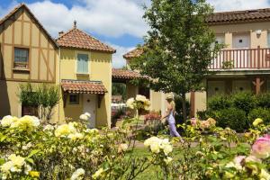 een vrouw die door een tuin loopt voor de huizen bij La résidence du Lac - maeva Home - Appartement 2 pièces 5 personnes - Conf 694 in Monflanquin