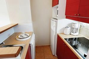 een kleine keuken met rode kasten en een witte koelkast bij La résidence du Lac - maeva Home - Appartement 2 pièces 5 personnes - Conf 694 in Monflanquin