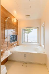 a bathroom with a tub and a window at ログコテージ風の丘 in Topetsu