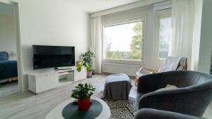 sala de estar con TV de pantalla plana y sofá en Spacious 68m2 apartment with fabulous forest view en Järvenpää
